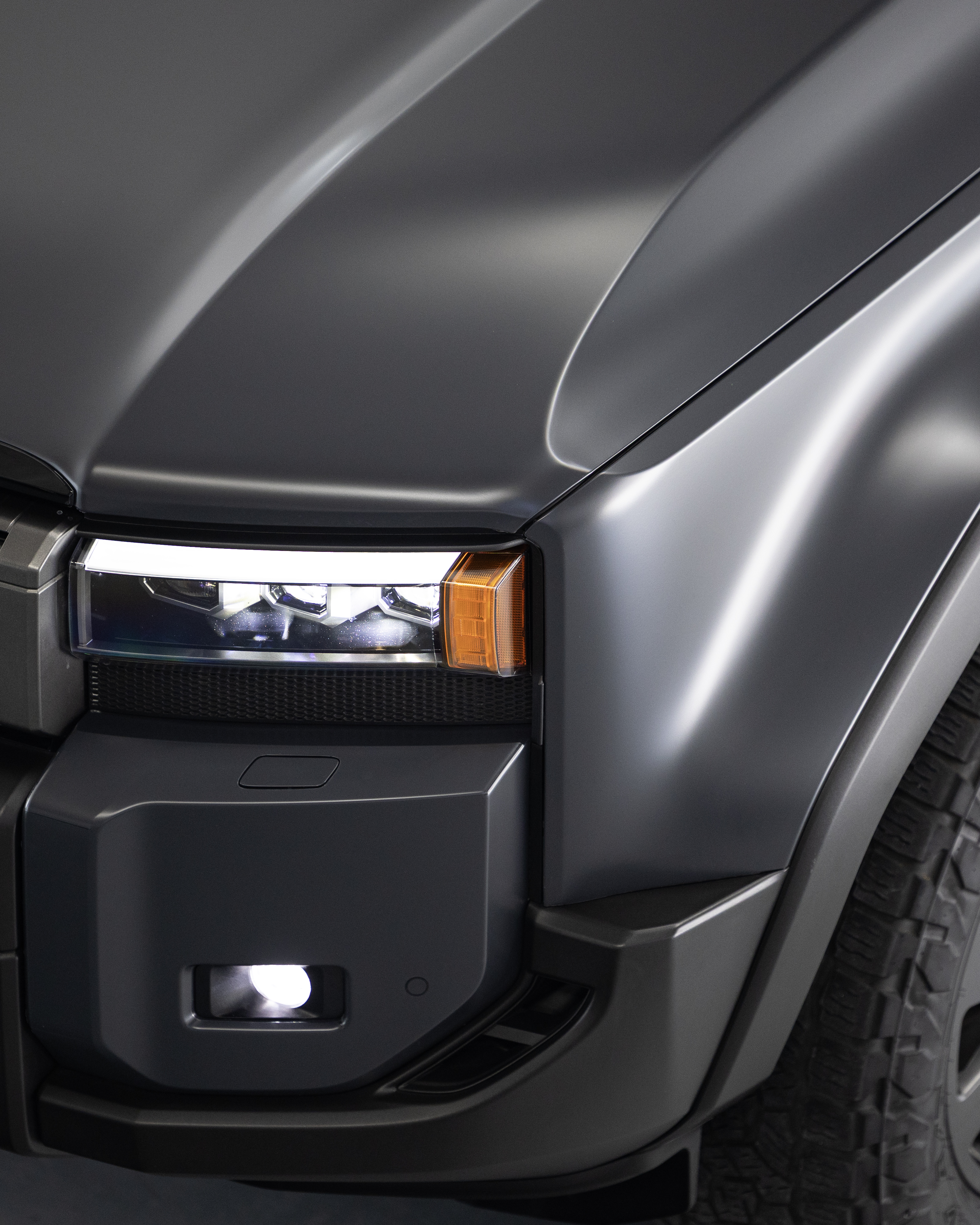 Close-up of Prado 250 headlight and bumper showing satin Stealth PPF finish detail