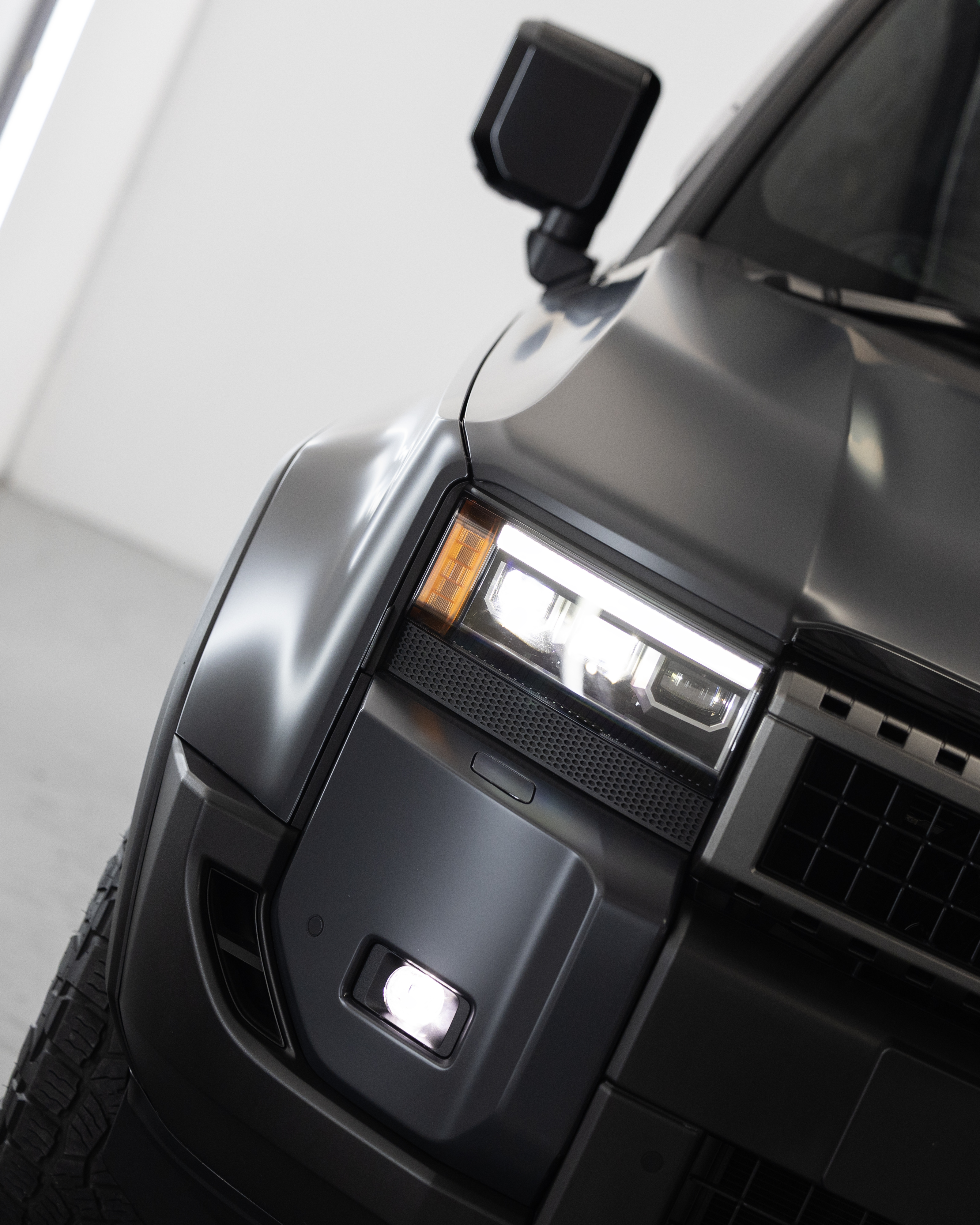 Wide angle close-up of Prado 250 headlight, guard and bumper wrapped in XPEL Stealth PPF